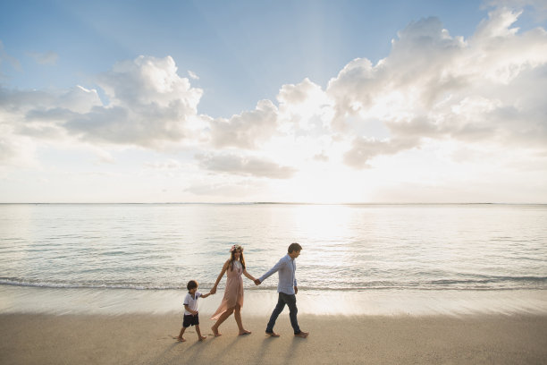怀孕的母亲，父亲和儿子在海滩上散步。图片下载