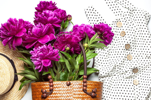 柳条稻草或藤妇女生态袋与美丽的粉红色牡丹花亚麻连衣裙草帽在白色背景。女性时尚配饰用牡丹花，春夏概念，卡用花图片下载