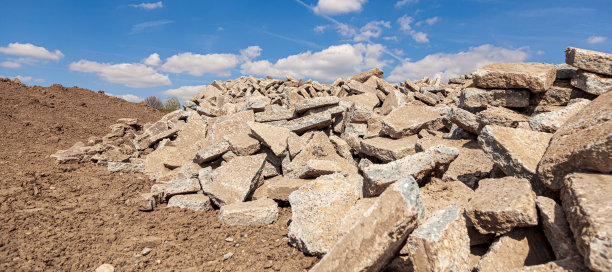 混凝土碎片堆在葡萄园地区的地面自然多云的天空。混凝土块堆放在土墩上。图片下载