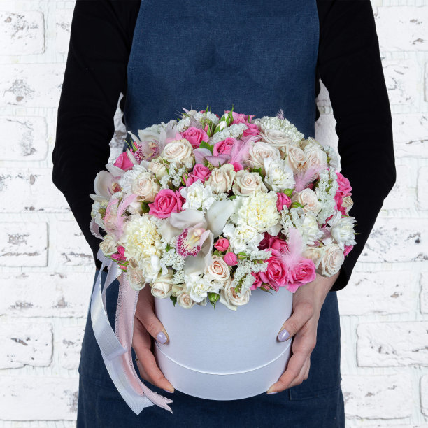 女花商拿着新做的鲜花花束在砖墙背景的盒子图片下载