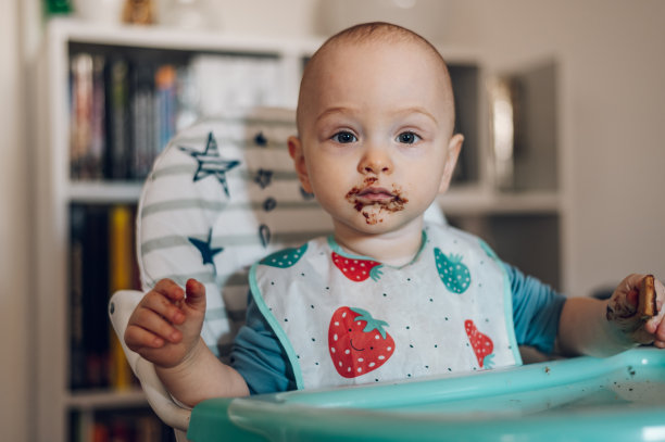 小男孩坐在餐椅上吃巧克力图片下载