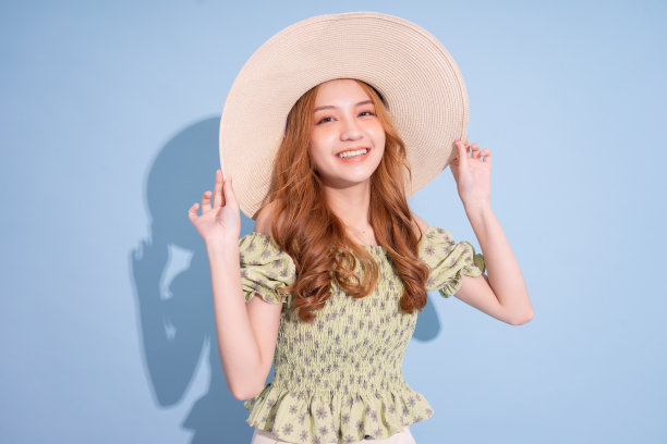 年轻的亚洲女孩肖像戴着蓝色背景的帽子图片下载