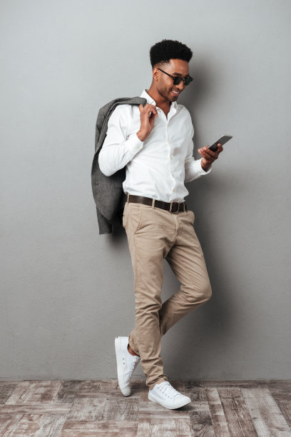 微笑的非洲人戴着太阳镜，把夹克扛在肩上图片下载