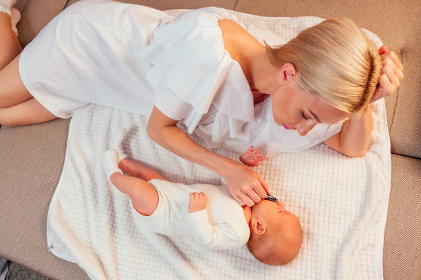 金发妈妈在舒适的公寓里母乳喂养和拥抱孩子图片下载