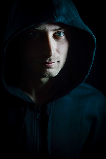 一个年轻的蓝眼睛男子的肖像与帽盖他的头谁在阴影中有一个严肃和坚定的表情图片下载
