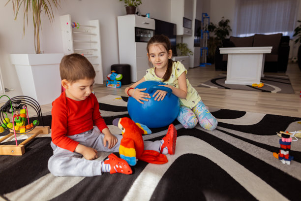 可爱的蹒跚学步的男孩正在和他的妹妹玩鹦鹉玩具图片下载