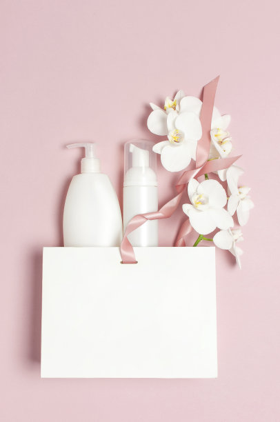 平铺俯视图白色化妆瓶容器礼品袋白色蝴蝶兰花在粉红色的背景。化妆品SPA品牌模拟天然有机美容产品概念极简主义风格图片下载