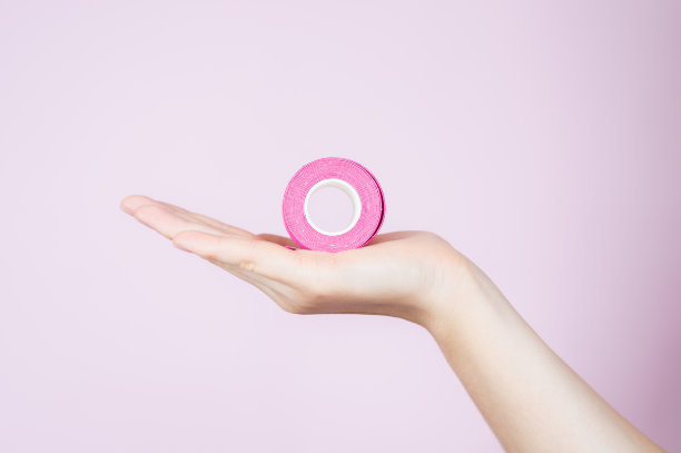 女人手里拿着粉红色的磁带卷孤立在粉红色。运动学，物理治疗，康复概念图片下载