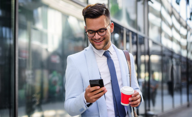 成功的商人站在公司面前，查看智能手机上的数据。商业、教育、生活理念图片下载