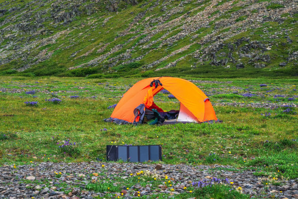 营地的太阳能电池。独自在风景如画的夏山徒步旅行。夏天在绿色多岩石的高原上露营。图片下载