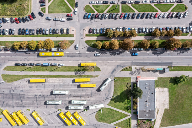 鸟瞰图巴士站与黄色巴士和停车场与停放的汽车。阳光明媚的城市风光。图片下载
