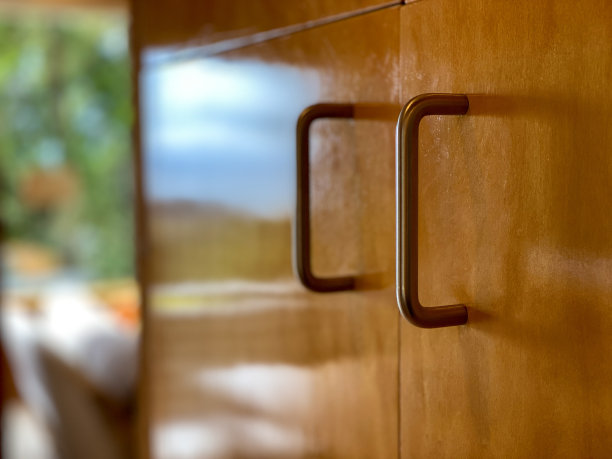 厨房木制橱柜上的金属弧形把手。图片下载