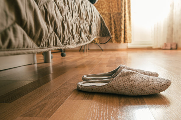 家里的拖鞋放在客厅床边的拼花地板上。图片下载