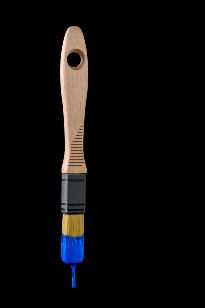 近景木制画笔与蓝色油漆滴在黑色背景。图片下载