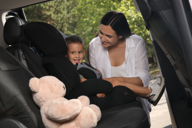 母亲用汽车安全带把儿子系在儿童座椅上图片下载