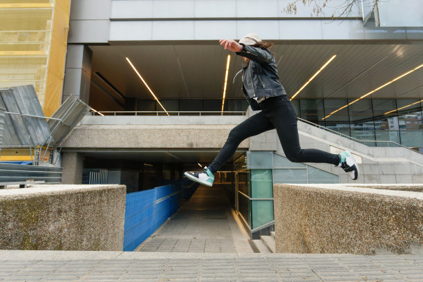 一个小女孩在城市的挡土墙之间跳跃图片下载