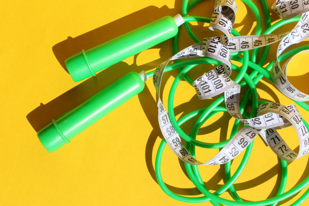 绿色的跳绳放在黄色的背景上。图片下载