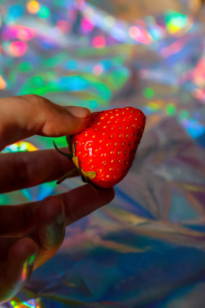 离焦特写手握成熟的红草莓对现代全息图背景。水果和浆果。收获和作物概念。有机食品。梯度。的焦点图片下载