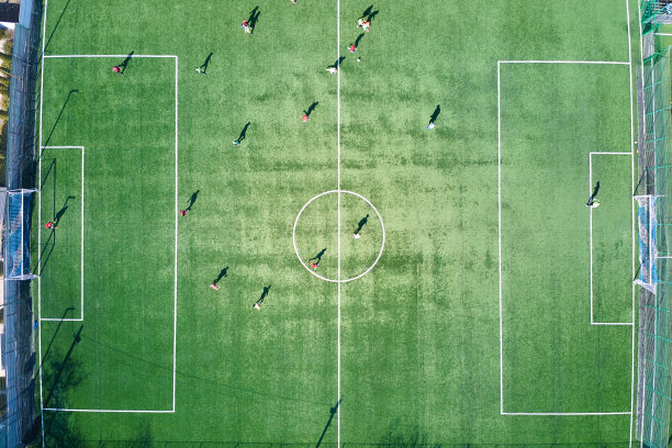 足球运动员在绿色体育场上踢足球的鸟瞰图。图片下载