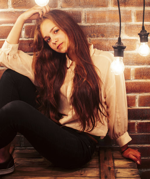 年轻的十几岁的女孩摆出欢快的姿势在现代阁楼工作室室内与许多灯，生活方式度假的人的概念图片下载