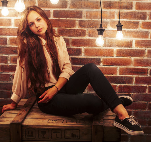 年轻的十几岁的女孩摆出欢快的姿势在现代阁楼工作室室内与许多灯，生活方式度假的人的概念图片下载