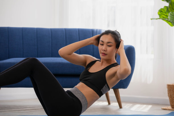 穿着运动服做仰卧起坐的亚洲女人。年轻女子在家做腹部运动。图片下载