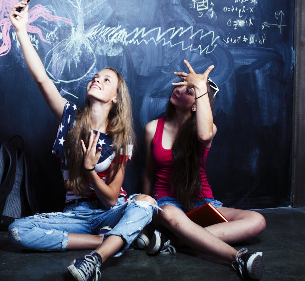 暑假后回到学校，两个十几岁的女孩在教室里用黑板涂漆图片下载