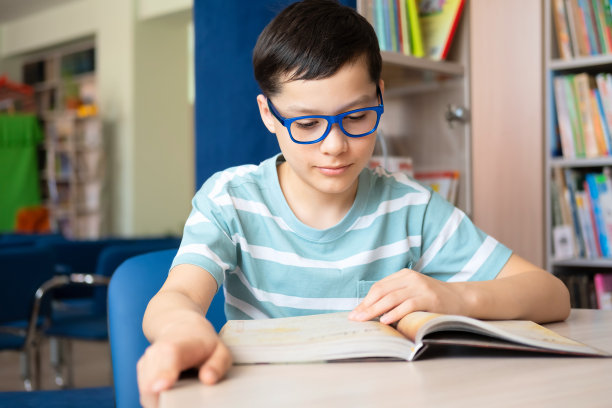 白人少年男孩在现代公共图书馆看书。学校和额外教育的概念。图片下载