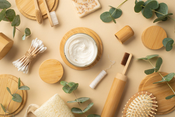 没有塑料的概念。顶部视图照片的瓶子与牙膏，天然化妆品，肥皂，牙线，牙刷，毛刷，棉花芽绿色的植物叶子和木站在孤立的米色背景图片下载