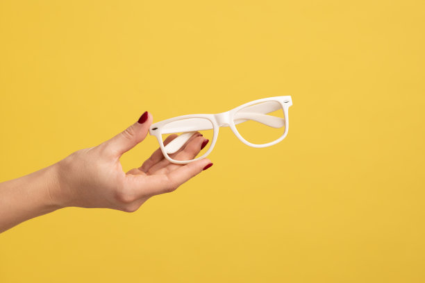 侧面视图特写的女人的手握和显示白色的眼镜框架。图片下载