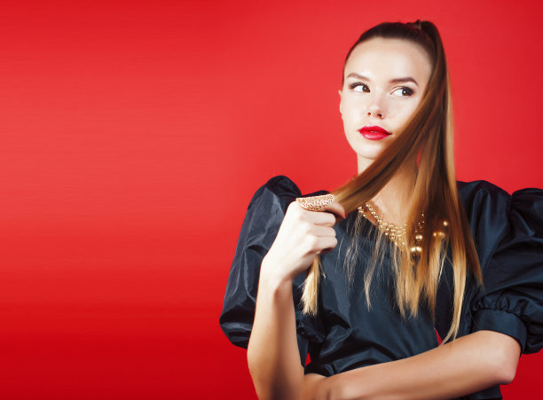 年轻漂亮的女人在红色背景上摆姿势，生活方式的人的概念图片下载