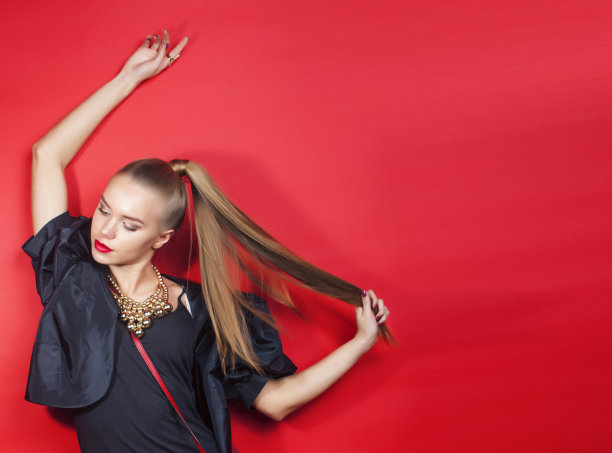 年轻漂亮的女人在红色背景上摆姿势，生活方式的人的概念图片下载