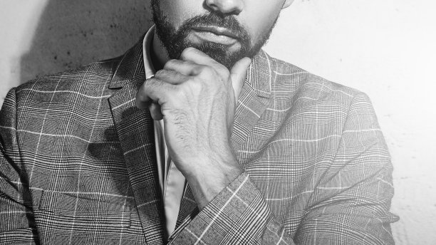 身穿灰色格子西装的男子靠在混凝土墙上摆姿势图片下载