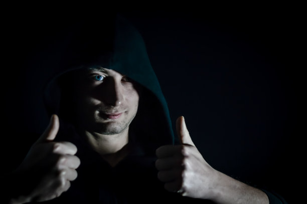 竖起大拇指——一个年轻的蒙面男子的肖像，他在树荫下用双手做了一个赞许的手势图片下载