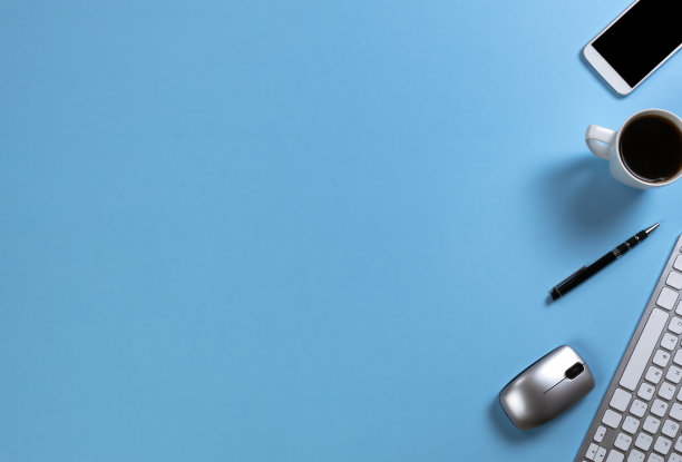 蓝色的办公桌面，配有电脑键盘，早餐咖啡和其他工作或学校的基本用品图片下载