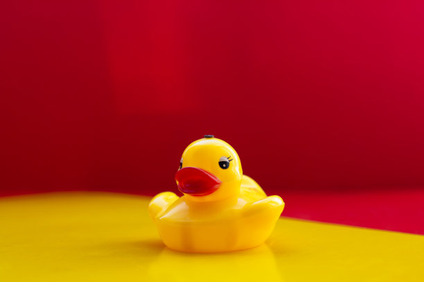 黄色橡胶鸭与大红唇在黄红色的背景与文字的空间。黄色的玩具鸭子。人工大嘴唇。肉毒杆菌的嘴唇。鸭嘴。本空间图片下载