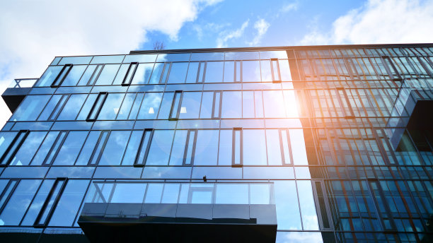 玻璃幕墙的现代办公大楼，背景是晴朗的天空。图片下载