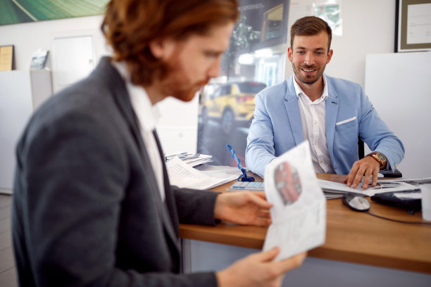 汽车销售沙龙的男人在看宣传册上的新车图片下载