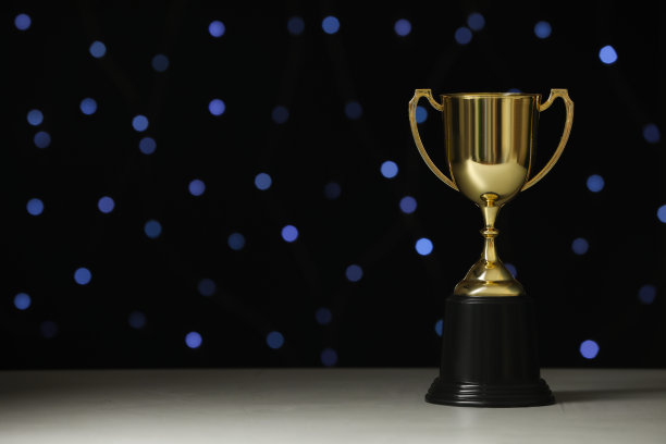 金色奖杯在白色的桌子上对模糊的节日灯光，文字的空间图片下载
