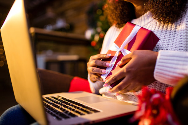 一个非洲女人在舒适的圣诞节室内用笔记本电脑网购。准备过圣诞节，准备冬季大甩卖图片下载