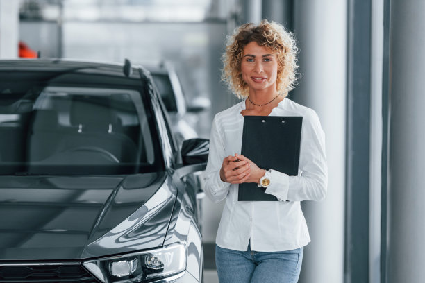 拿着记事本。一个金发卷发的女人在自动沙龙里图片下载