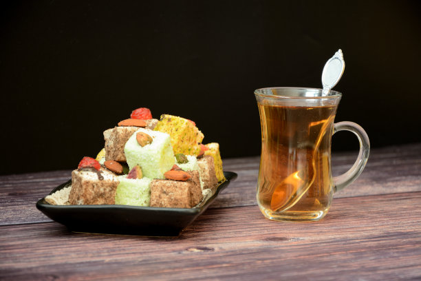 一个盘子与各种土耳其糖果和一杯热nay在一个木桌。图片下载