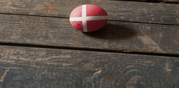 丹麦国旗，画在一个鸡蛋在木板上。丹麦复活节画彩蛋。复活节图片下载