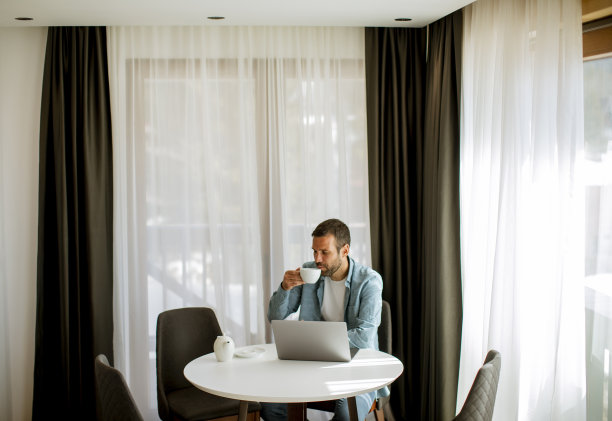 年轻人在客厅里用笔记本电脑喝茶图片下载