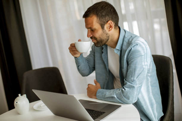 年轻人在客厅里用笔记本电脑喝茶图片下载