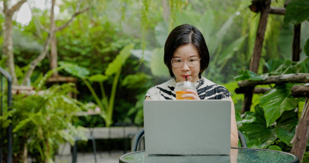 亚洲女商人坐在工作中使用笔记本电脑在暑假期间在花园进行在线会议。女游客在外工作投资，网上销售。商务休闲旅游概念图片下载