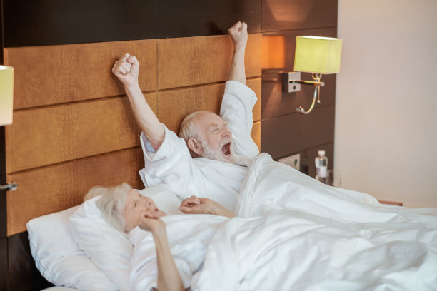 一对老夫妇早上在床上伸懒腰打哈欠图片下载