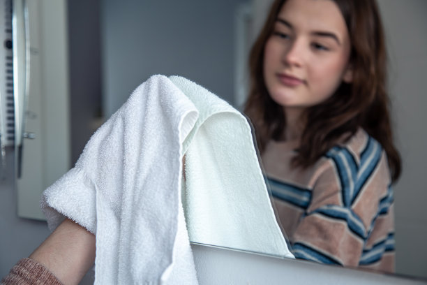 一位年轻女子用抹布擦镜子。图片下载