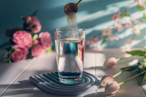 用汤匙将胶原蛋白粉倒入一杯水中图片下载