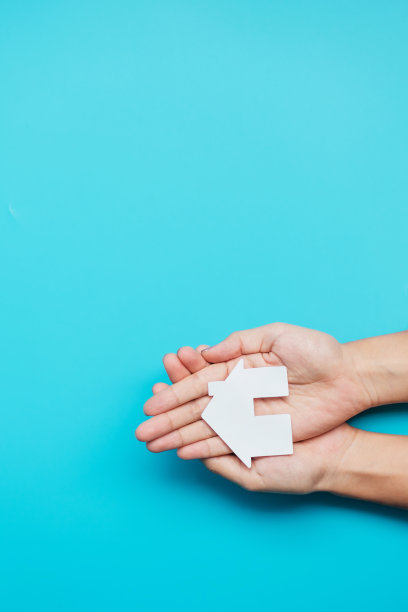 手握纸在家剪纸蓝色背景。房地产，抵押，保险，租金，幸福家庭，无家可归，寄养和家庭日的概念图片下载